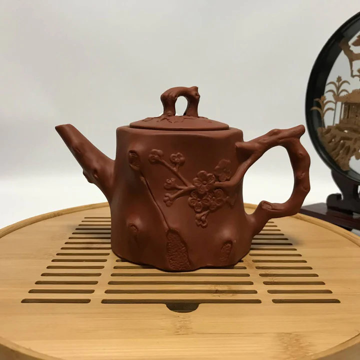 Clay teapot shaped like a tree trunk with carved plum blossom