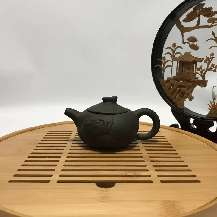 Small dark green-grey clay teapot with a smooth rounded body