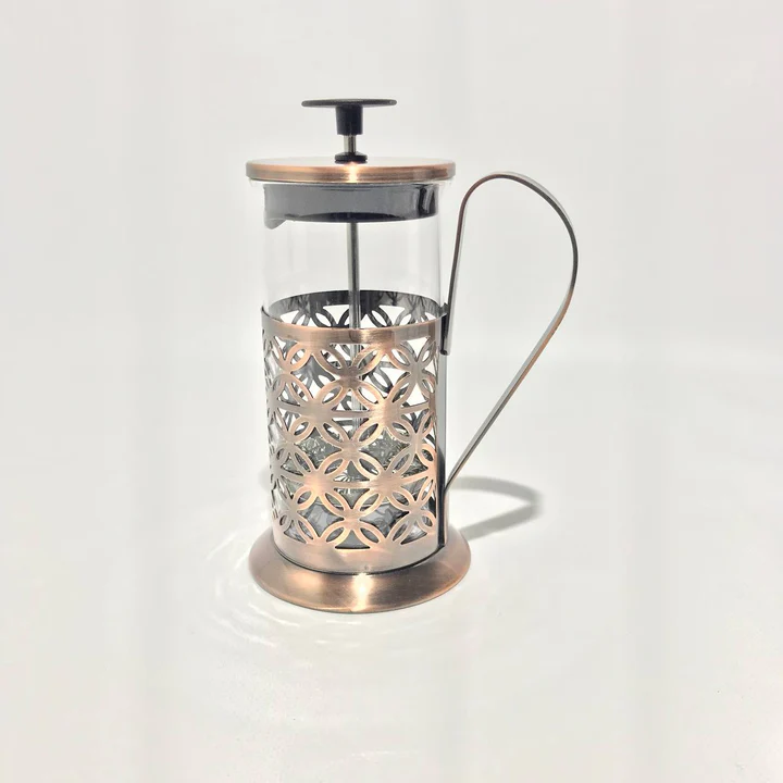 Glass tea press with a patterned copper-tone metal frame