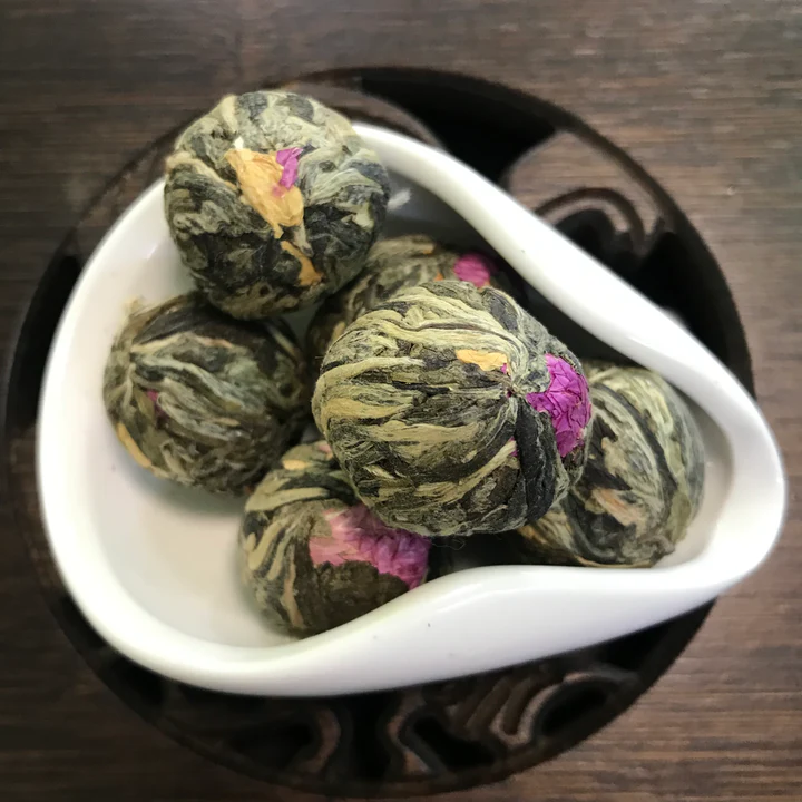 Green tea balls set with pink and orange flowers in a white dish