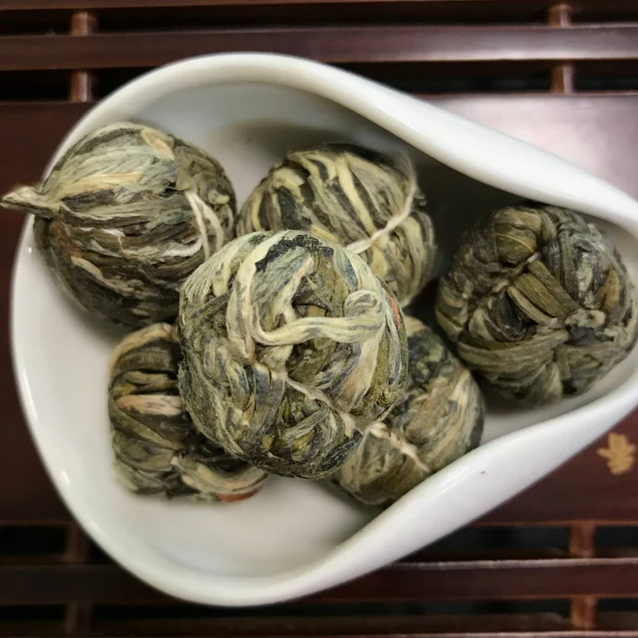 Blooming tea balls with bright pink aster flowers in a white dish