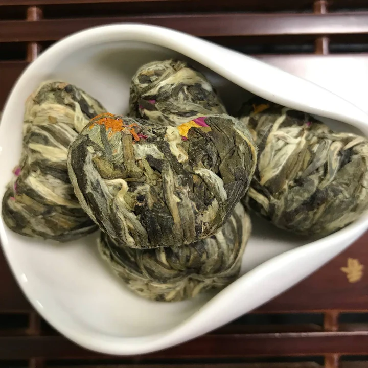 Pale silvery hand-rolled blooming tea balls in a white dish